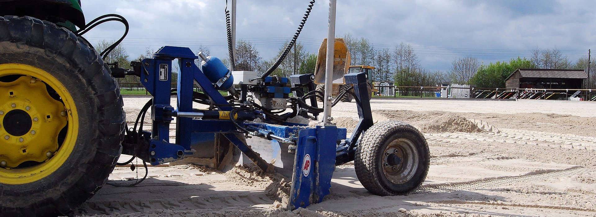 Bau eines Reitplatzes mit Planiermaschine und Traktor auf Sandboden
